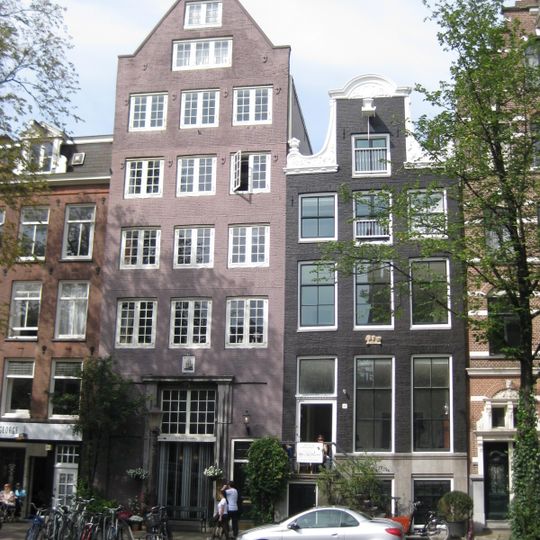 Pand met halsgevel met rijk gebeeldhouwde vleugelstukken, vazen en beeldhouwwerk in de afdekking