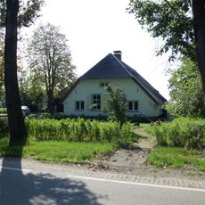 Boerderij, wit gepleisterd bakstenen gebouwtje onder een afgewolfd rieten zadeldak