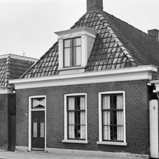 Eenvoudig pand met zesruitsvensters onder schilddak met versierde dakkapel