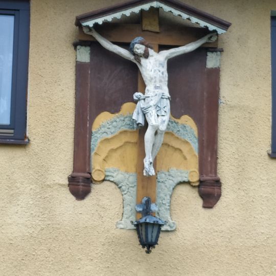 Pamětní kříž na zdi domu na křižovatce ulic Benešova a Komenského ve Sloupu v Čechách