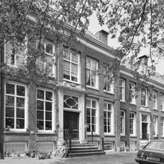 Pand met vooruitspringende sobere lijstgevel en stoep, versiering boven de deur