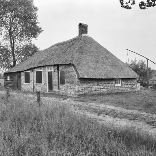 Eenvoudige bakstenen boerderijtje onder rieten kap met aangebouwde houten, gepotdekselde schuur