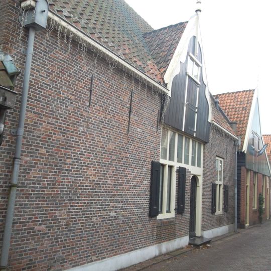 Huis met dwars zadeldak tussen twee topgevels met vlechtingen