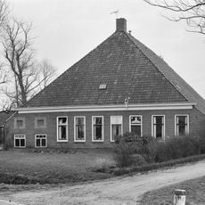 Grote stelphoeve met zes smalle woonhuisvensters ter weerszijden van de ingang, twee melkkeldervensters met siernissen en met stookhut