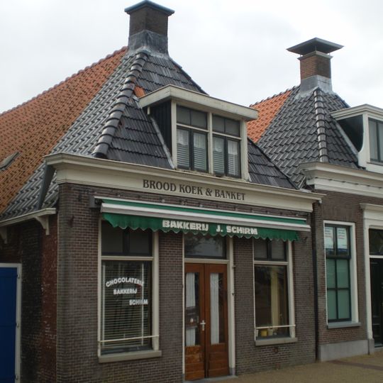 Eenvoudig pand onder zadeldak met voorschild gedekt door Friese pannen waarboven schoorsteen