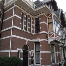 Pand met neo-renaissancegevel. Rechts een afgeknotte puntgevel met houten voorschot. Leeuwenmasker-sluitstenen, vakwerk, vlechtwerk en sierankers