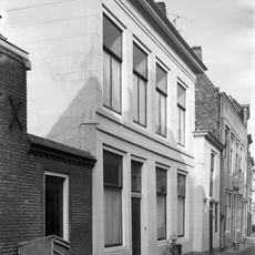 Huis met gepleisterde lijstgevel. Aansluitend zijbouw. Rozetbovenlicht. Stoep