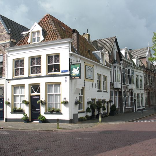 Hoekpand met gepleisterde gevels met houten kroonlijst aan de Graafschap onder zadeldak met voorschild