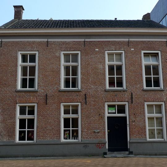 Rechthoekig pand onder met oud-Hollandse pannen gedekte dwarskap tussen puntgevels bekroond met schoorstenen