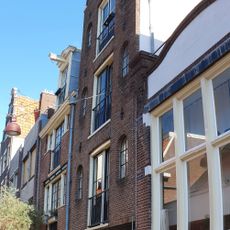 Pand met gevel onder vaag klokvormige top met rollagen