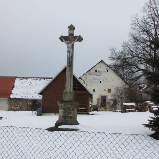 Kříž v severní části Janovic v zahradě čp.7