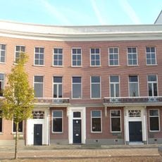 Pand, onderdeel van een reeks herenhuizen, gebouwd in een gebogen rooilijn. Bakstenen lijstgevel. Balcon op consoles en met gietijzeren balustrade