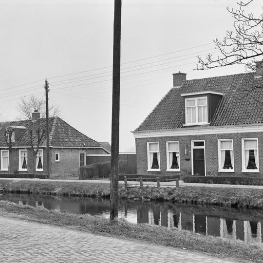 Pand met omgaande goot op klosjes onder hoog schilddak met twee hoekschoorstenen