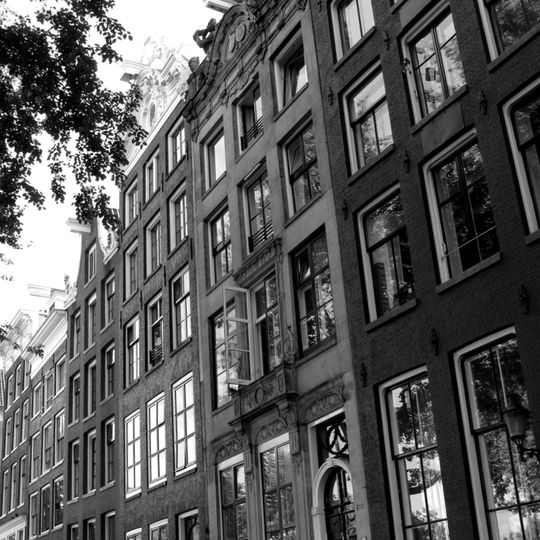 Pand met zandstenen gevel onder rijk gebeeldhouwde verhoogde lijst en attiek, met gebeeldhouwde stoep, pui en middenpartij