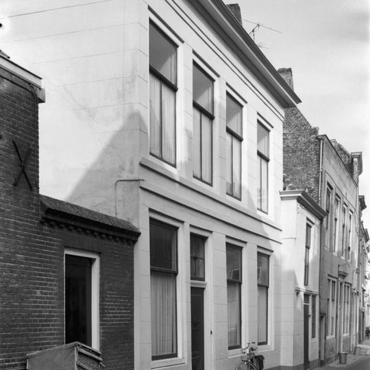 Huis met gepleisterde lijstgevel. Aansluitend zijbouw. Rozetbovenlicht. Stoep