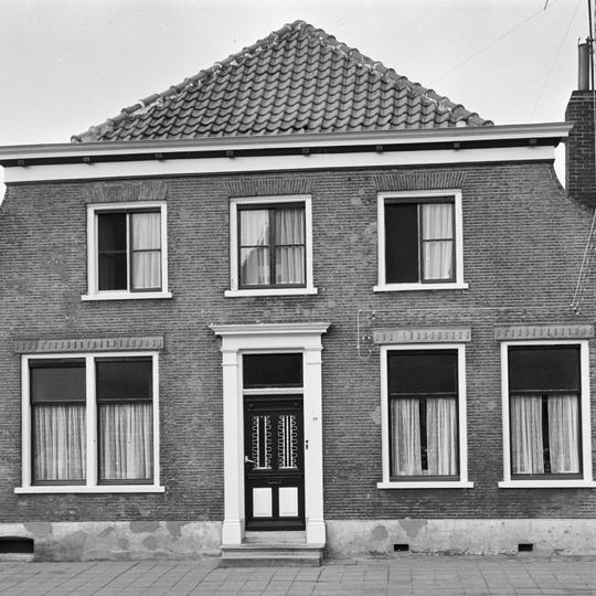 Huis onder schilddak en met lijstgevel waarvan de bovenhoeken ingezwenkt zijn