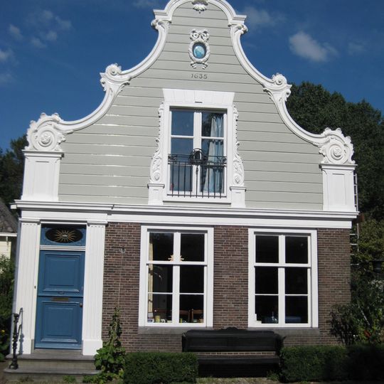 Houten dijkhuis met klokgevel in Lodewijk XV-stijl uit circa 1760, bakstenen onderpui uit circa 1800