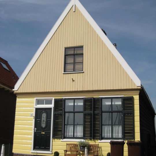 Houten huis. Puntvormig voorschot. Goede pui, en puilijst, goede roedenverdeling. Gepotdekselde zijwanden