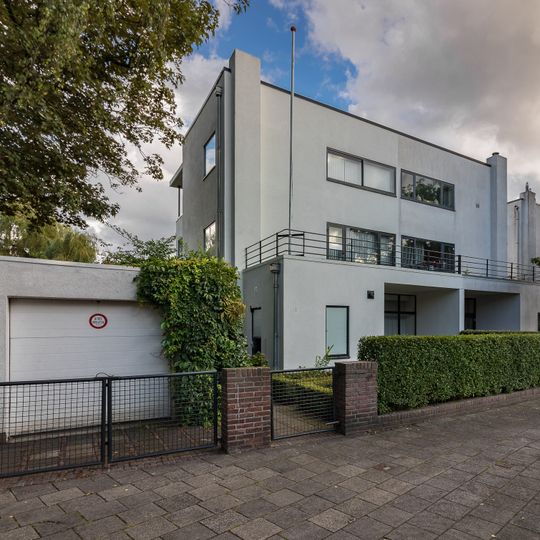 Vrijstaand, in baksteen opgetrokken, witgepleisterd, rechtafgesloten, vlakgedekt blok van twee woonhuizen