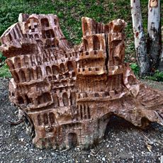 Tocón de eucalipto tallado a modo de escultura simulando un edificio o ciudad medieval abigarrada.