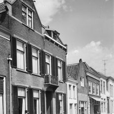 Pand met verdieping en hoog schilddak. Lijstgevel, eerste helft 19e eeuw, met in de verdieping negenruitsschuiframen