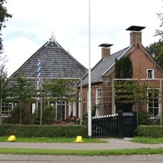 Kop-hals-rompboerderij met topgevels met zesruitsvensters, lijsten met boeiborden en topschoorstenen met borden