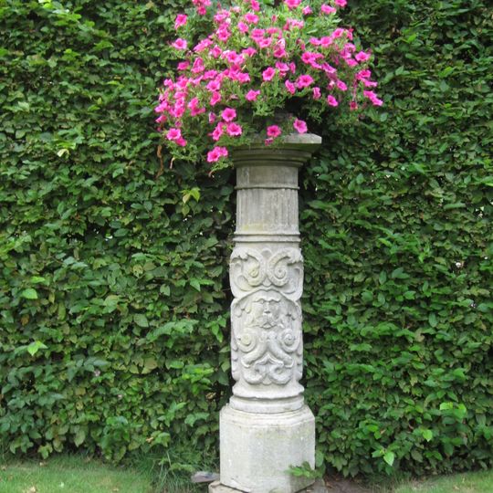Warmelo, sokkel met gietijzeren vaas in rozentuin