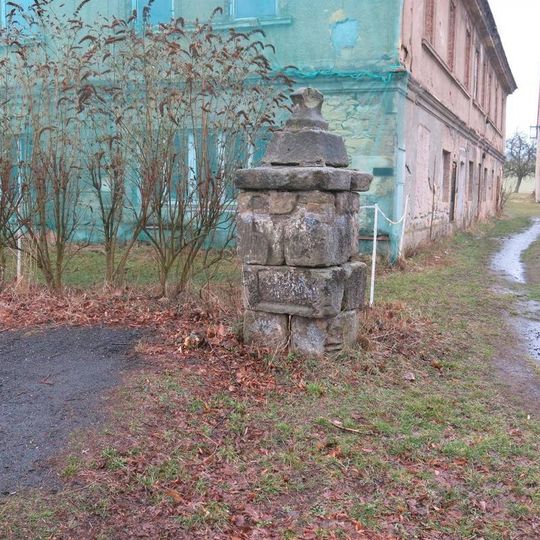Podstavec ulomeného kříže na návsi v Ostrém