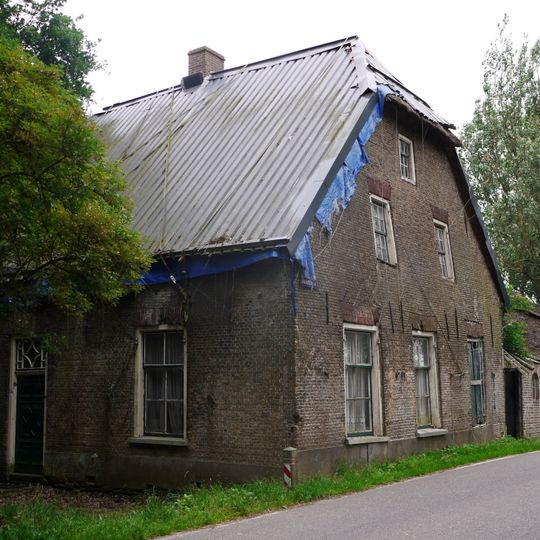 Boerderij met hoog, rieten wolfdak en rode strekken boven de vensters