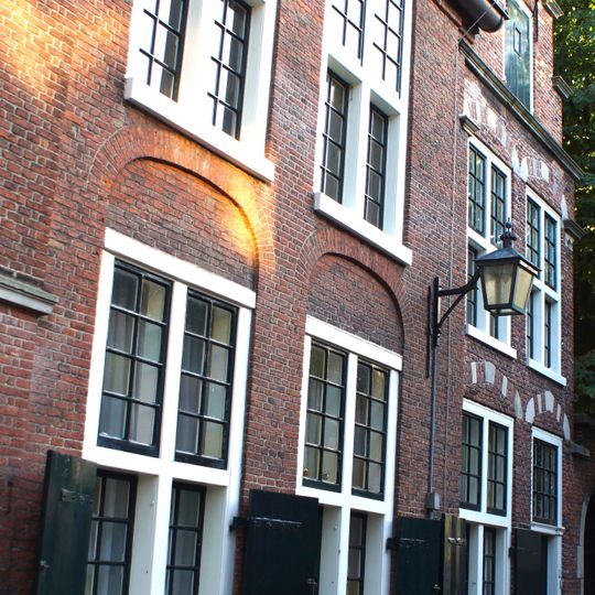 Naast de kerk kosterij met trapgevel en kruisvensters, metselwerk met blokken versierd. Boogpoort in gotische trant met natuurstenen omlijstingen