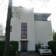 Vrijstaand, in baksteen opgetrokken, gepleisterd, uit in hoogte en omvang verschillende, kubische bouwvolumen samengesteld, vlakgedekt woonhuis