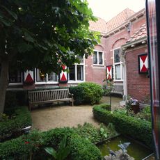 Pand zonder verdieping pand onder zadeldak gebouwd ter huisvesting van de dameskamer en gelegen aan binnenplaats tegenover de herenkamer, uitgevoerd in neo-renaissancestijl.