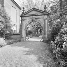 Toegangspoort met jonische halve zuilen die een hoofdgestel met fronton dragen