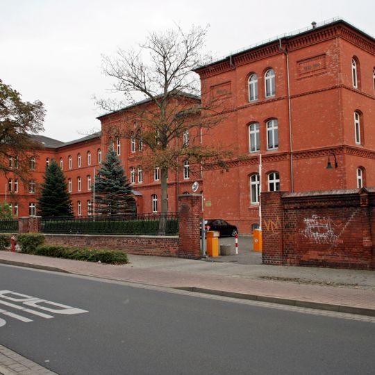 Schule, mit Einfriedung, Grünfläche vor der Schule und Turnhalle im Schulhof Dübener Straße 20