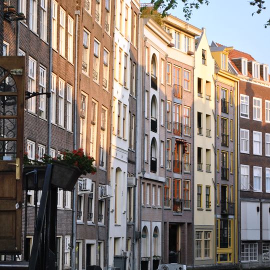 Ten dele een pakhuisachtig karakter vertonend pand met gevel onder klokvormig topje met rollagen