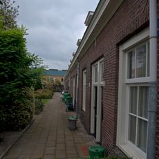 Dubbele rij van vierentwintig rug-aan-rug gebouwde woningen, op rechthoekige plattegrond bestaande uit een bouwlaag onder een met pannen gedekt mansardedak
