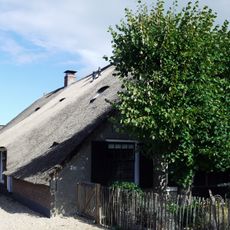 Boerderij met gepleisterde voorgevel met afgewolfd dak