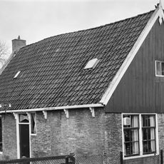 Eenvoudig pand onder zadeldak tussen topgevels, waarvan een met houten voorschot