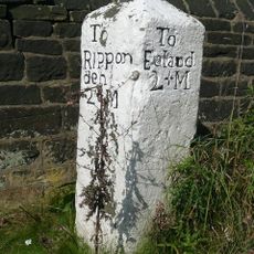 Milestone set against churchyard wall on south west