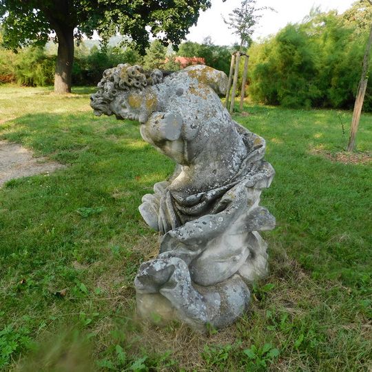 Socha klečící postavy v zámeckém parku ve Slavkově