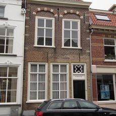 Huis met lijstgevel waarin geprofileerde tooglijsten op maskers plat dak