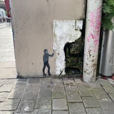 P'tit Zom qui repeint le mur en blanc. Pochoir de l’artiste Ender réalisé pendant le festival Points de Vue 2024.