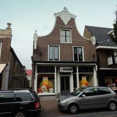 Pand onder zadeldak tegen klokgevel met gebeeldhouwde aanzetkrullen, lijst en bekroning