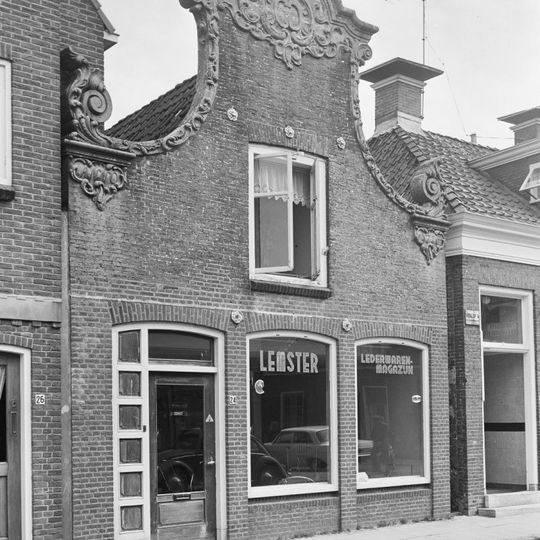 Pand onder zadeldak tegen met beeldhouwwerk in de plaatselijke trant der late 18e eeuw versierde klokgevel