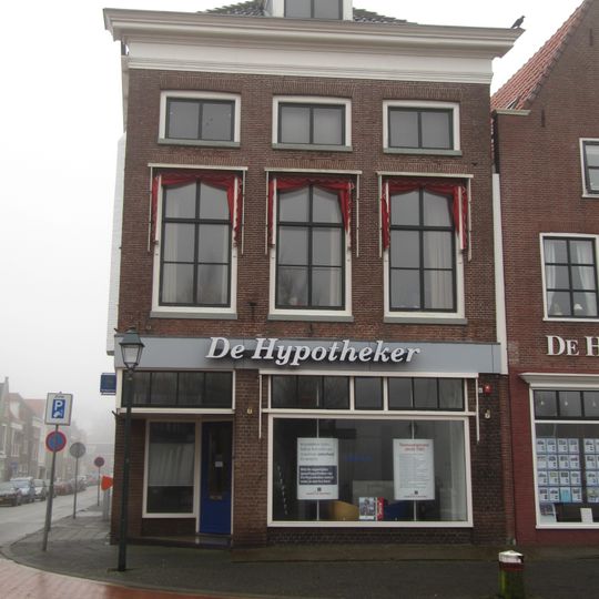 Hoekpand met lage zolderverdiepingvensters, rechte kroonlijst waarboven dakkapel en twee topschoorstenen