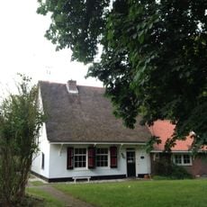 Dienstwoninkje in het duin, witgepleisterd, topgevel, met riet gedekt, terzijde bakhuisje