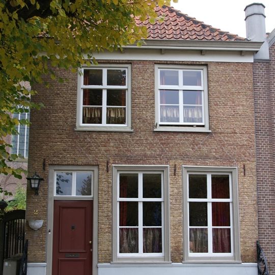 Huis onder met rode pannen belegd schilddak en met lijstgevel in schoon werk