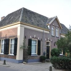 Eenvoudige boerderij met muurankers en luiken voor de vensters