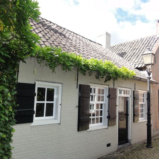 Eenvoudig landarbeidershuisje, onder pannen zadeldak tussen puntgeveltjes met rollagen