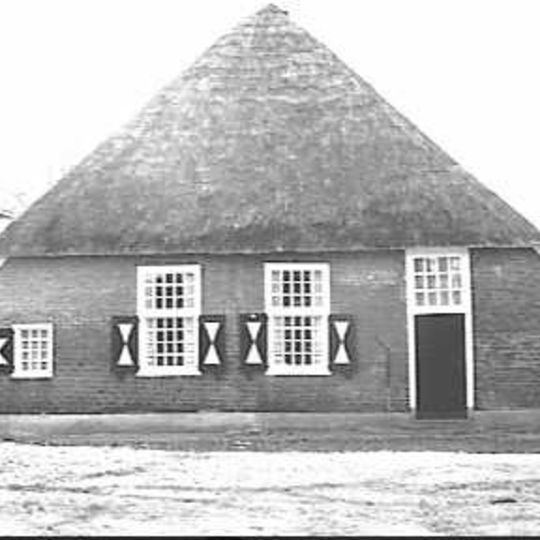 Boerderij onder laag rieten schilddak; onderschoer. De vensters hebben kalf, roedenverdeling en halve luiken